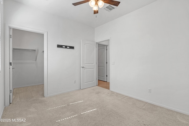 unfurnished bedroom with a spacious closet, baseboards, visible vents, and carpet floors