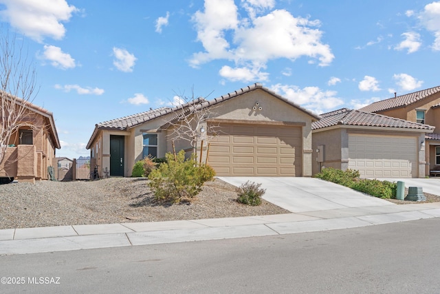 view of front of house featuring stucco siding, an attached garage, a tile roof, and driveway