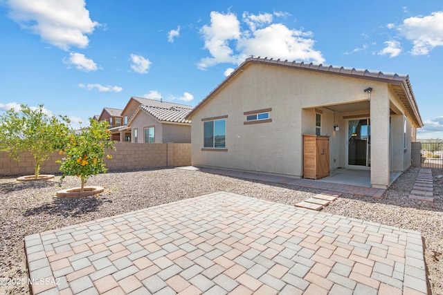 rear view of property with a patio area, stucco siding, a tiled roof, and a fenced backyard