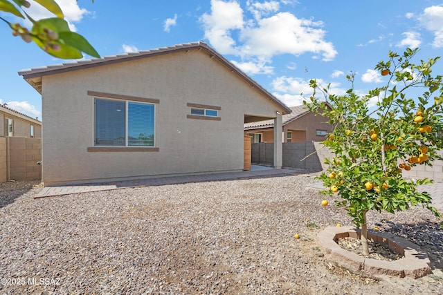 rear view of property featuring stucco siding, a fenced backyard, and a patio area