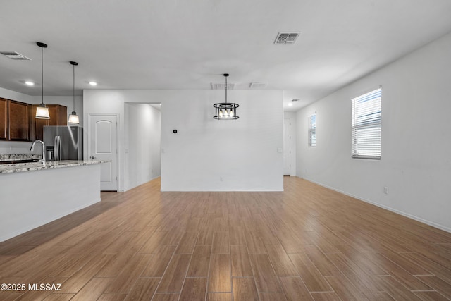 unfurnished living room with light wood finished floors, visible vents, and recessed lighting