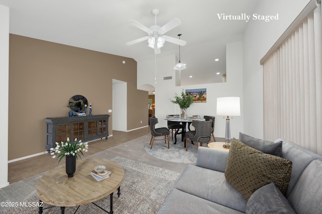 living room featuring visible vents, baseboards, arched walkways, high vaulted ceiling, and a ceiling fan