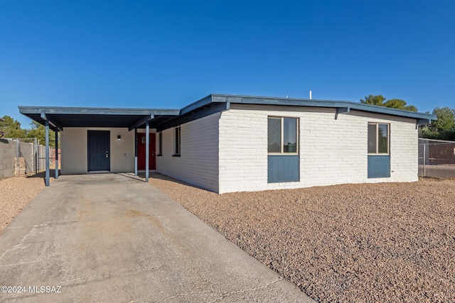 view of front of home with fence, an attached carport, concrete driveway, and brick siding