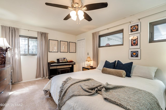 bedroom featuring a closet, light colored carpet, baseboards, and a ceiling fan