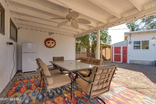 view of patio / terrace with an outbuilding, outdoor dining space, a ceiling fan, and fence