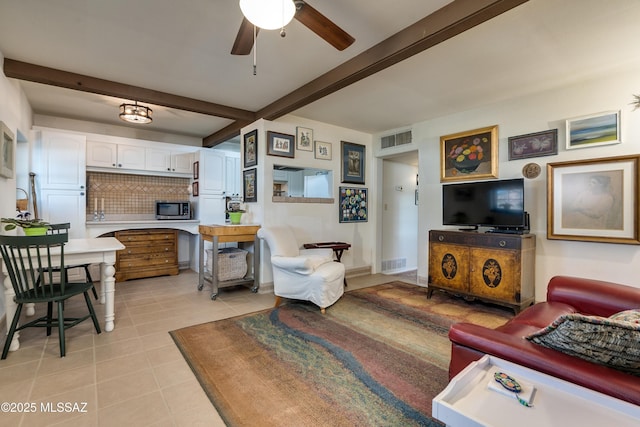 living room featuring beamed ceiling, light tile patterned flooring, and visible vents