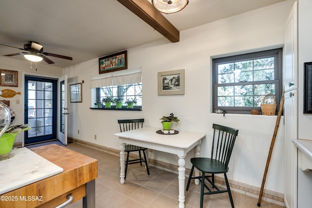 dining room featuring beam ceiling, light tile patterned floors, a healthy amount of sunlight, and baseboards