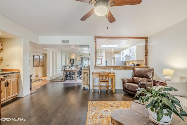 living room with dark wood-type flooring, rail lighting, visible vents, and a ceiling fan