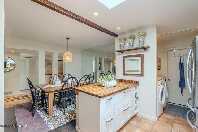 kitchen with a skylight, visible vents, butcher block counters, freestanding refrigerator, and white cabinetry