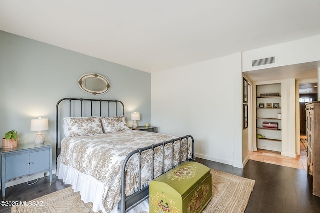 bedroom with wood finished floors, visible vents, and baseboards