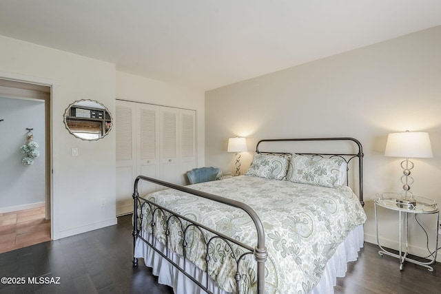 bedroom with a closet, wood finished floors, and baseboards