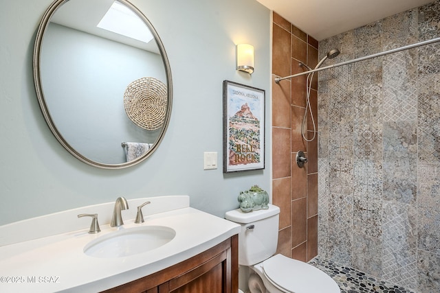 bathroom with vanity, a tile shower, and toilet