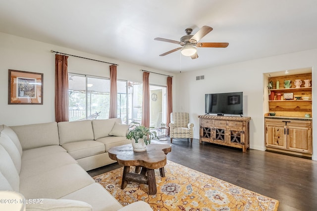 living area featuring dark wood-type flooring, visible vents, and a ceiling fan