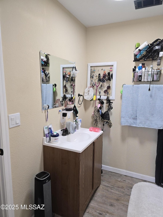 bathroom featuring visible vents, baseboards, wood finished floors, and vanity