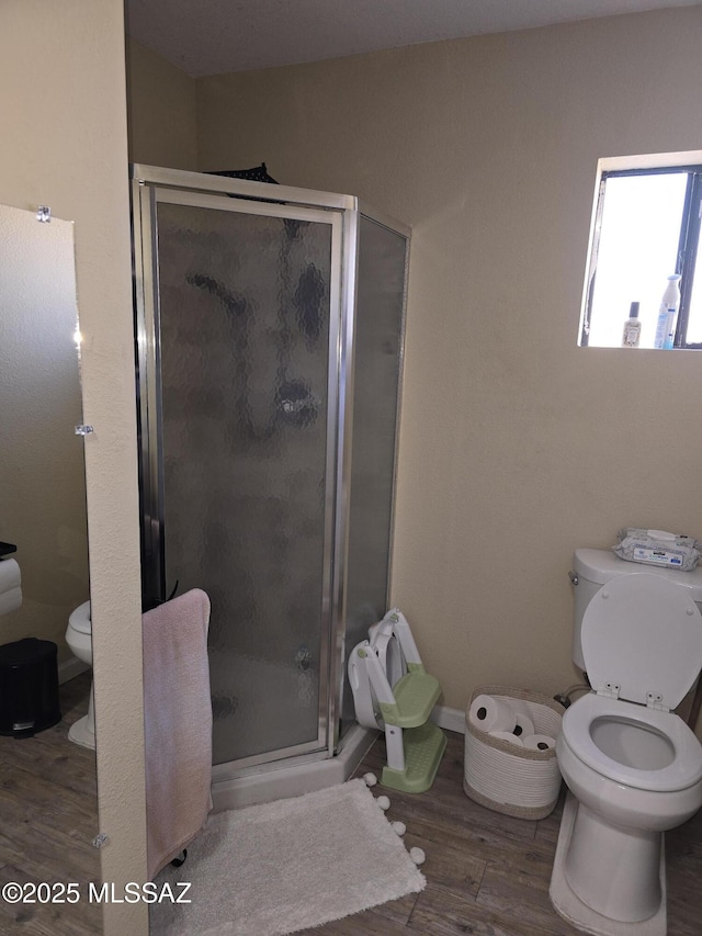 bathroom featuring a stall shower, toilet, and wood finished floors