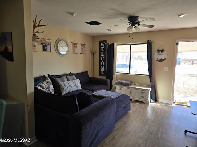 living room with visible vents, baseboards, a ceiling fan, and wood finished floors