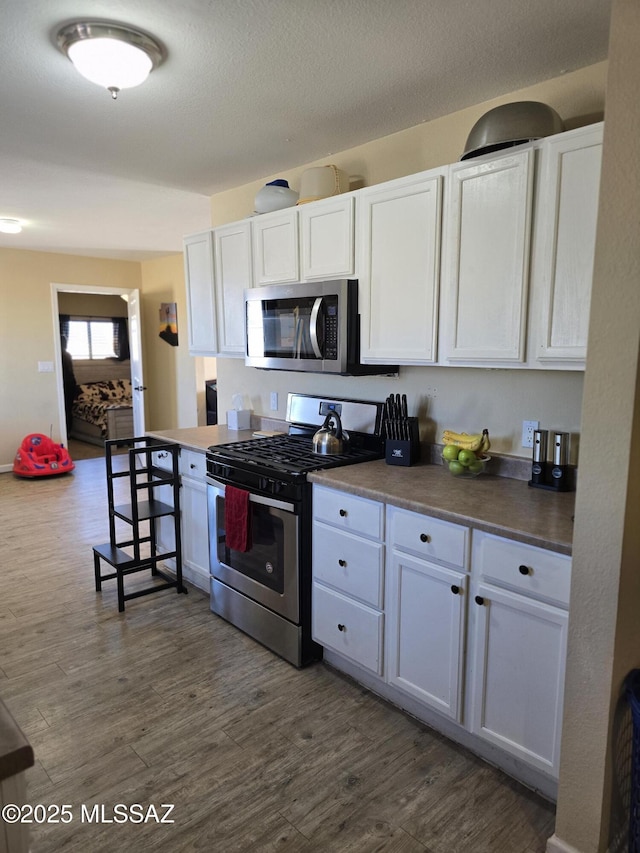 kitchen with white cabinetry, dark wood-type flooring, and stainless steel appliances