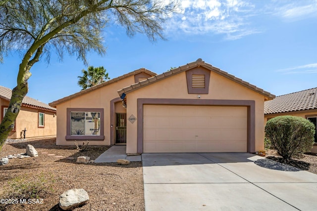 view of front of house featuring concrete driveway, a tiled roof, a garage, and stucco siding