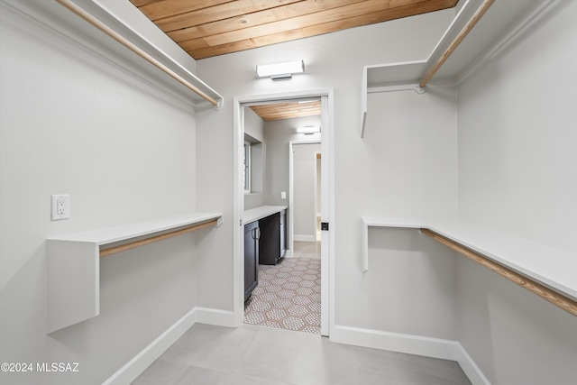 tiled spare room featuring wood ceiling, baseboards, and beam ceiling