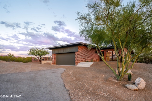 view of front facade featuring aphalt driveway, brick siding, and a garage