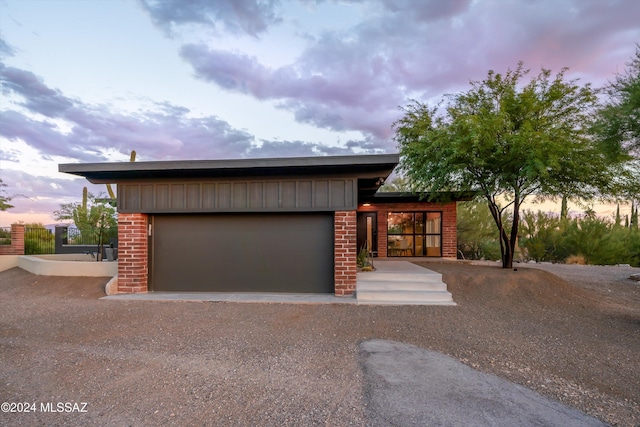 view of front of house featuring board and batten siding, driveway, brick siding, and a garage