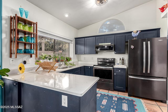 kitchen featuring lofted ceiling, light tile patterned floors, a peninsula, a sink, and appliances with stainless steel finishes