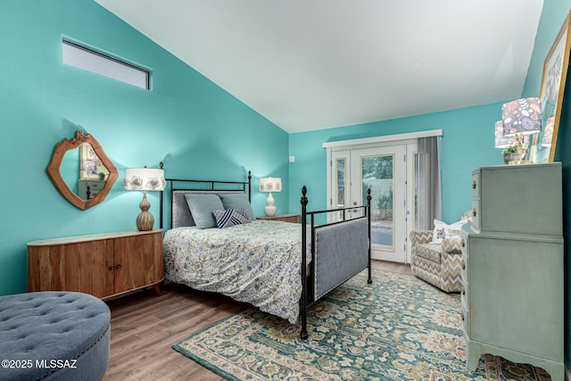 bedroom with lofted ceiling, multiple windows, wood finished floors, and access to exterior