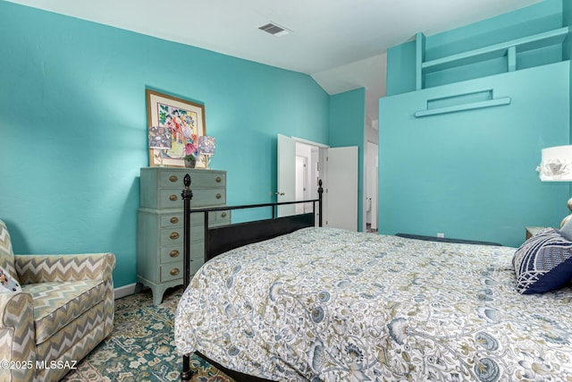 bedroom with lofted ceiling, visible vents, and baseboards