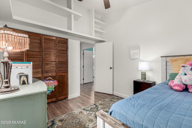 bedroom featuring a ceiling fan, a high ceiling, baseboards, and wood finished floors