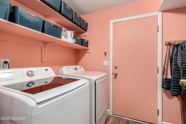 washroom with light wood-type flooring, laundry area, baseboards, and washer and clothes dryer