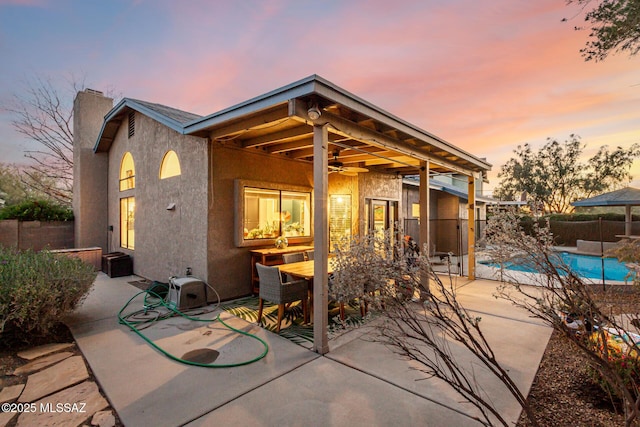 rear view of property featuring a patio, outdoor dining space, fence, and stucco siding