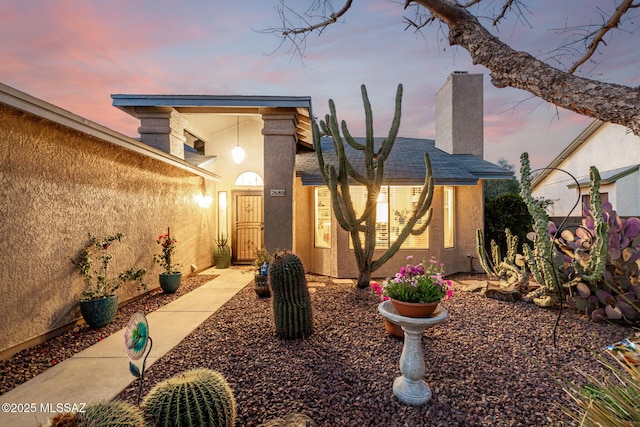 view of front of property featuring a chimney and stucco siding