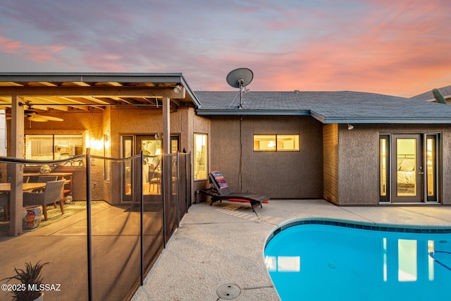 pool at dusk with a patio area and an outdoor pool