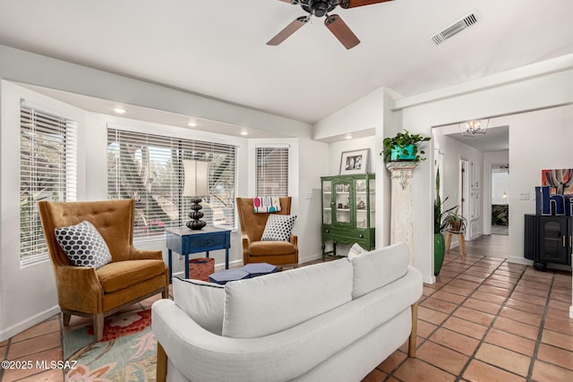 living area featuring light tile patterned floors, lofted ceiling, visible vents, baseboards, and ceiling fan with notable chandelier