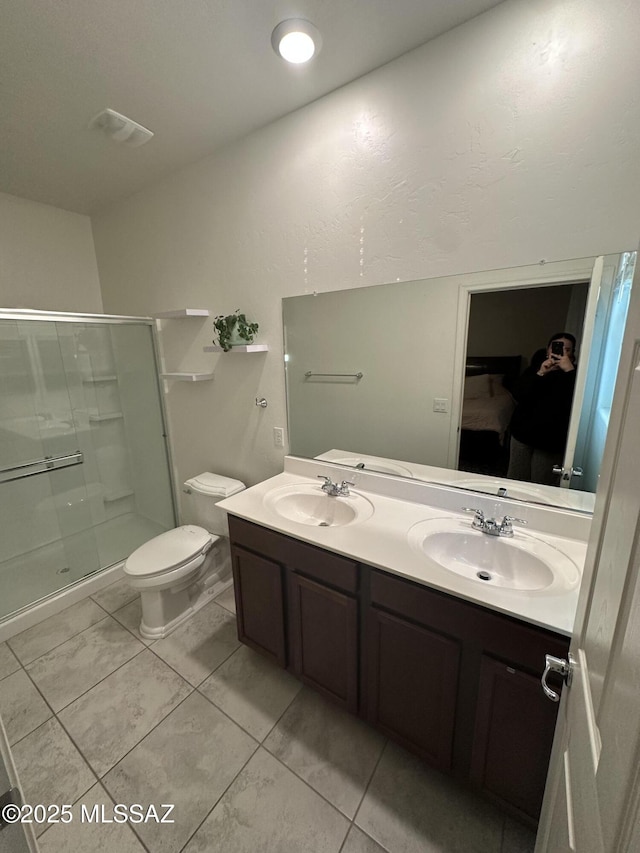 bathroom with double vanity, toilet, a stall shower, and a sink
