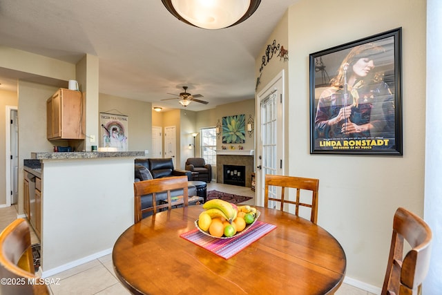 dining room with light tile patterned floors, ceiling fan, and a fireplace