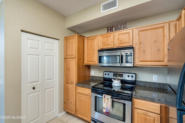 kitchen featuring appliances with stainless steel finishes, tile counters, visible vents, and light brown cabinetry