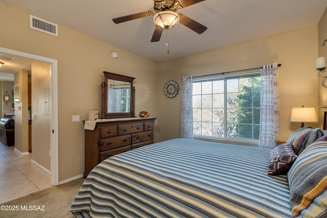 bedroom featuring baseboards, visible vents, light colored carpet, ceiling fan, and light tile patterned flooring