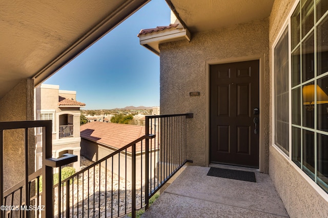 property entrance featuring a balcony, a tiled roof, and stucco siding