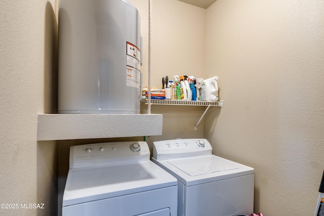 laundry room with laundry area, a textured wall, washer and dryer, and electric water heater