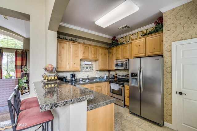 kitchen featuring tile counters, appliances with stainless steel finishes, a sink, a peninsula, and wallpapered walls