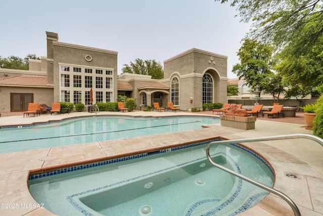 community pool with french doors, a patio area, and a hot tub