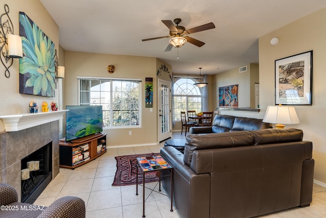 living room featuring light tile patterned floors, visible vents, ceiling fan, a tile fireplace, and baseboards