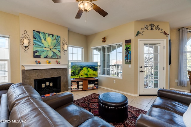 tiled living area featuring baseboards, a ceiling fan, and a tile fireplace