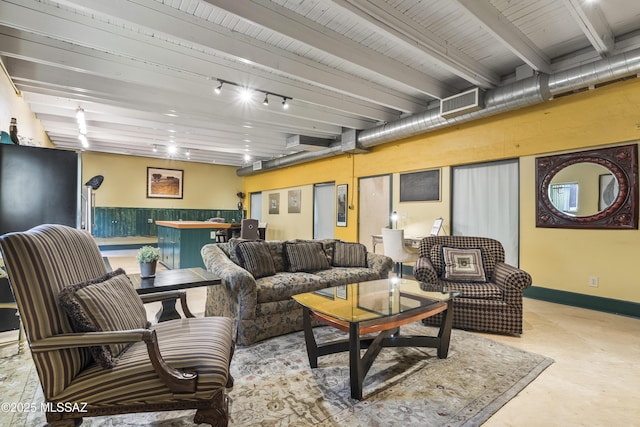 living area with beam ceiling, concrete floors, rail lighting, and baseboards