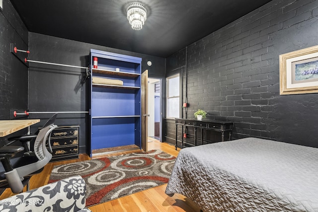 bedroom with brick wall and wood finished floors