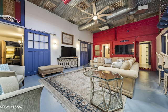 living area with visible vents, ceiling fan, a towering ceiling, and finished concrete floors