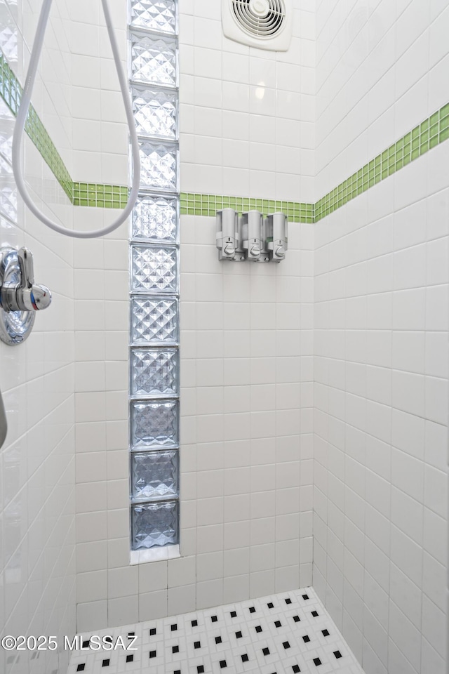 full bathroom featuring a tile shower and visible vents