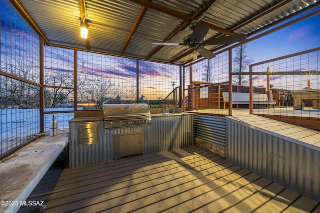 deck at dusk with ceiling fan, an outdoor kitchen, and area for grilling