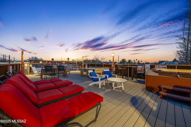 deck at dusk featuring a hot tub